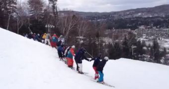 30 skiers hold hands in preparation for a backflip