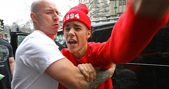 Older photo of Justin Bieber making a run for a paparazzo, while his bodyguard is restraining him