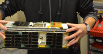 CINEMA systems engineer Jerry Kim showcases the CubeSat, in January 2012