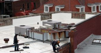 A construction crew paints a white roof in downtown Washington DC