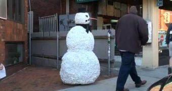 A guy dressed in a snowman costume patiently stands still in the street awaiting for his next prank victims
