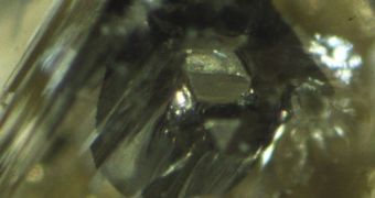 Below this diamond's surface is a hexagonal grain of iron sulfide surrounded by a black rim
