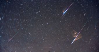 Meteors streak across the sky against a background of star trails in this long-exposure image.