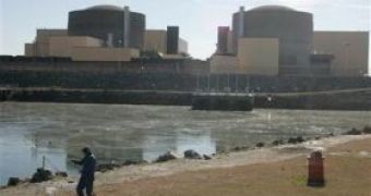 Image of a man fishing in the warm waters of a lake near a nuclear power plant