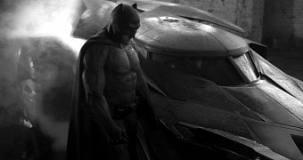 Ben Affleck in the Batsuit, standing and brooding next to the Batmobile