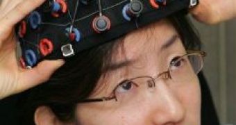 Hitachi, Ltd. researcher Akiko Obata takes off a head gear following a demonstration of a new technology that reads brain activity and lets you control everyday objects without lifting a finger