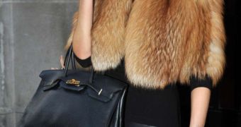 Victoria Beckham in fur and dangling an expensive Hermes Birkin bag on her arm, of which she reportedly has 100