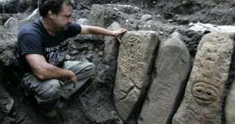 Puerto Rican archaeologist Hernan Bustelo sits next stones etched with ancient petroglyphs and graves that reveal unusual burial methods in Ponce, Puerto Rico.