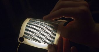 Graduate student Miles Barr hold a flexible and foldable array of solar cells that have been printed on a sheet of paper