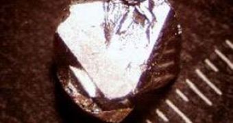 A single crystal of YFE2Zn20 shown next to a millimeter scale.