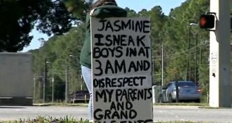 15-year-old Jasmine's stands on the corner of a busy street, wearing an embarrassing sign