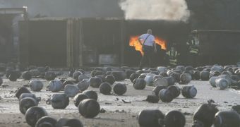 Firefighters collect blown up propane cylinders
