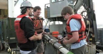 Oceanographers David C. Smith, Robert Pockalny and Franciszek Hasiuk prepare to remove a sediment core from the coring device