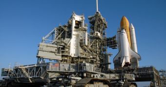 A booster and its shuttle are towed to the launch pad by heavy equipment