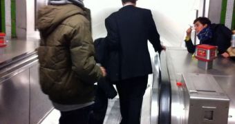 A Japanese businessman stumbles down the stairs in a subway station