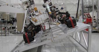 The image shows Curiosity on a tilt table in the Spacecraft Assembly Facility at JPL