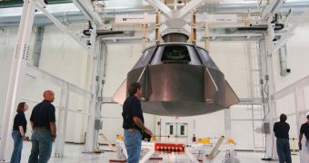 A production assembly crew lowers a full-scale Orion mockup onto the crew module holding structure