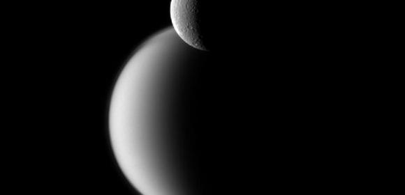 Rhea Backdropped by Titan in New Cassini Image