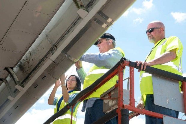 NASA materials scientist Mia Siochi and systems engineer Mike Alexander, together with Boeing technician Felix Boyett, count insect residue on the right wing of the Boeing’s ecoDemonstrator 757