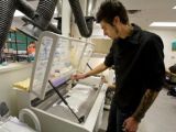 Grant Marchelli, a UW mechanical engineering graduate student, removes a new object from the Solheim Lab printer. Marchelli led development of the first method for 3D printing in glass