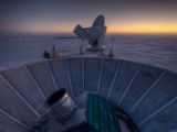The Sun sets behind BICEP2 (in the foreground) and the South Pole Telescope (in the background)