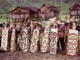 Asmat warriors with shields. In the background, palafitos