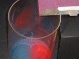The blue and red grains spontaneously separate when they are shaken and fall into a waiting beaker below.