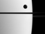 Dione seen crossing the face of Saturn