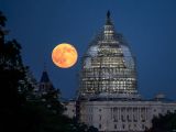 View of a full moon next to the scaffold-shrouded U.S. Capitol; the photo was taken on July 31, 2015 in Washington